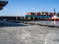 a dock with containers in the water and a big red boat in the water near the docks