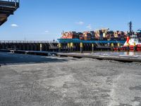 a dock with containers in the water and a big red boat in the water near the docks