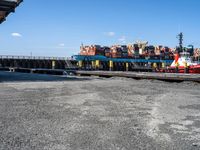 a dock with containers in the water and a big red boat in the water near the docks