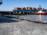 a dock with containers in the water and a big red boat in the water near the docks