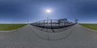 a fisheye lens of the road and fence as seen from below it's intersection