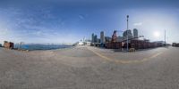 fish eye view of container yard with water in background and city skyline on horizon in foreground