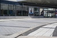 a person sitting at the bench in front of a mall that is empty of people