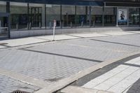 a person sitting at the bench in front of a mall that is empty of people