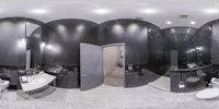 a bathroom with double sinks and mirrors and a toilet in it, surrounded by black tiled walls