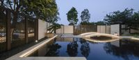 the water and stone walkway are illuminated at night in the courtyard area of the contemporary home