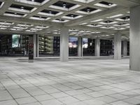 a concrete floor sitting under a perforied roof in a large building with several windows