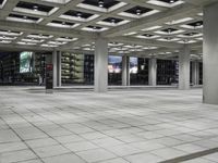 a concrete floor sitting under a perforied roof in a large building with several windows