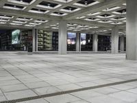 a concrete floor sitting under a perforied roof in a large building with several windows