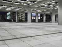 a concrete floor sitting under a perforied roof in a large building with several windows