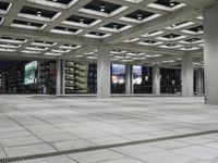 a concrete floor sitting under a perforied roof in a large building with several windows