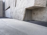 a man on a skateboard goes up a ramp in front of a building with cement walls