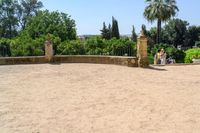 an old stone building is surrounded by palm trees and bushes near the gate to the entrance of the park