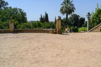 an old stone building is surrounded by palm trees and bushes near the gate to the entrance of the park