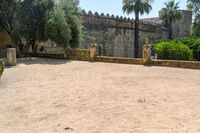 an old stone building is surrounded by palm trees and bushes near the gate to the entrance of the park