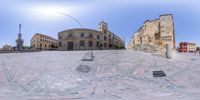 this is a fisheye lens image taken from the ground of a city plaza with the sun shining