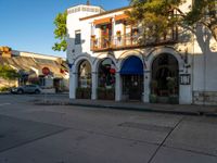 the corner of a store with arches on a street in the city during the day