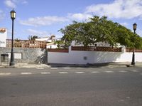 the corner of a street with fence and trees on the sides of it in a white walled area