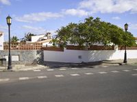 the corner of a street with fence and trees on the sides of it in a white walled area