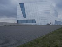 a building with white paint on it in front of a brick walkway under a gray cloudy sky