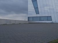 a building with white paint on it in front of a brick walkway under a gray cloudy sky