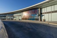 an airport building with a giant poster on it's side and a ramp for luggage