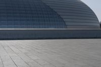 a person on a skateboard in front of a big building with a curved roof