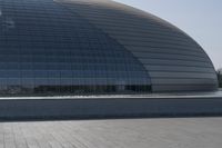 a person on a skateboard in front of a big building with a curved roof