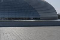 a person on a skateboard in front of a big building with a curved roof