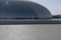 a person on a skateboard in front of a big building with a curved roof