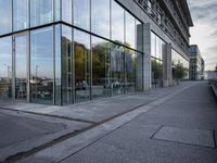 a side view of a building with glass on a street by the water's edge