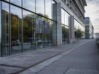 a side view of a building with glass on a street by the water's edge