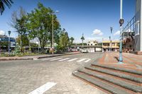 some steps leading up a street and buildings and trees in the distance and white lines on ground