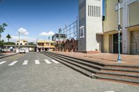 empty city street with steps leading to the entrance and building next to it, under a blue sky