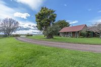 a large country house with an outside garage is located in the middle of a lush green field