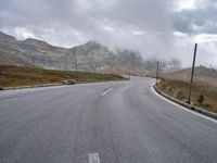 an empty country road with cars and mountains in the background on a stormy day for the arrival of spring