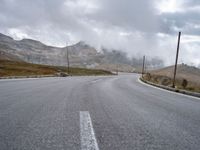 an empty country road with cars and mountains in the background on a stormy day for the arrival of spring