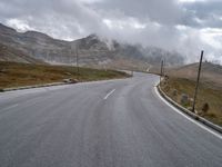 an empty country road with cars and mountains in the background on a stormy day for the arrival of spring