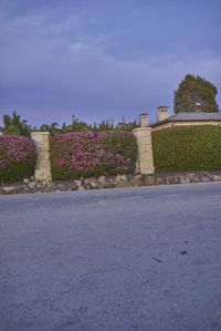 this is an image of a road in the country side with flowers and a building