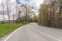 an empty country road runs along the woods on either side of the road, in the center of a forested area with trees