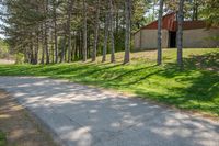 a country road with trees on either side and a grassy hill behind it at the side