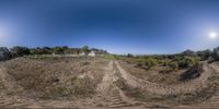 a 360 - turn view of a dirt road on a hill in the countryside with the house and trees in the background