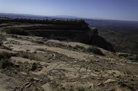 a couple hikes up a steep rocky hill to a cliff overlook overlooking a beautiful landscape