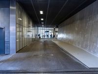 a man and a woman walking down a hallway in an empty building with glass walls