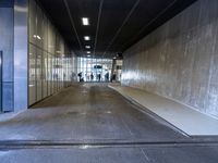 a man and a woman walking down a hallway in an empty building with glass walls