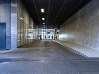 a man and a woman walking down a hallway in an empty building with glass walls