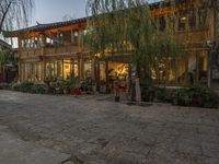 a couple walking outside of a store next to plants and trees on the street,