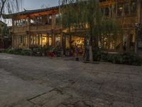 a couple walking outside of a store next to plants and trees on the street,