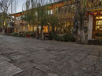 a couple walking outside of a store next to plants and trees on the street,