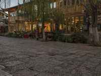 a couple walking outside of a store next to plants and trees on the street,